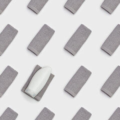 Geometric pattern with bath towels grey colored. Folded Cotton soft towel, white plastic bottle for gel or shampoo.
