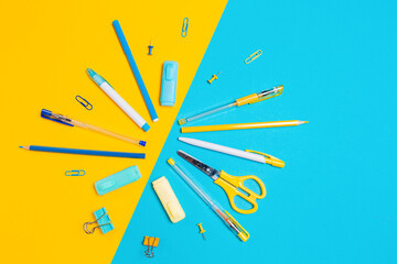 Composition of office supplies on blue and yellow background. Flat lay. Concept of back to school