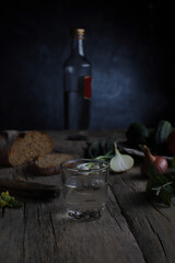 a glass of vodka and fresh vegetables for a snack on a vintage table
