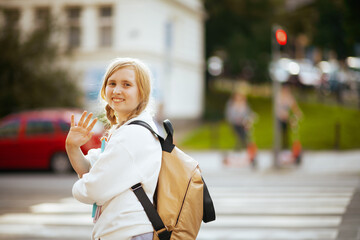 girl crossing crosswalk, hand waving and going to school
