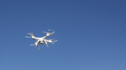 The drone flies against the background of a clear bright blue sky