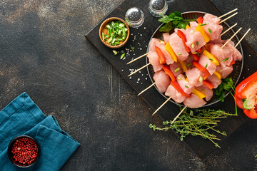 Raw shish kebab on wooden board, spices, herbs and vegetables on dark grey background. Barbecue Raw...
