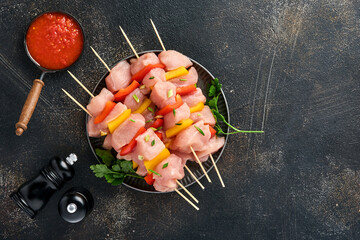 Raw shish kebab on wooden board, spices, herbs and vegetables on dark grey background. Barbecue Raw...