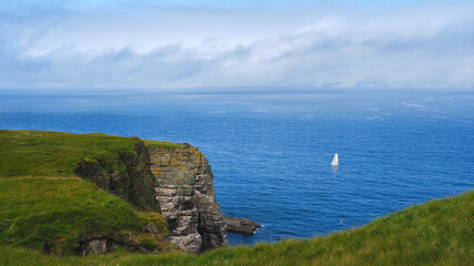 Fototapeta na wymiar Catamaran sailing off the cliffs of Handa Island in the Highlands of Scotland