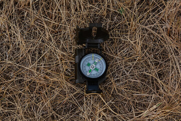 The compass lies on dry grass. Travel symbol.