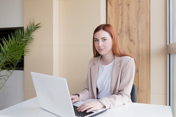 Serious business woman working on laptop sitting at office desk