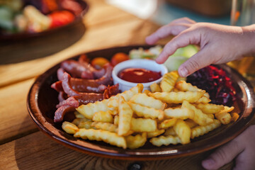 Kids favourite food - french fries, fried potatoes and sausages with vegetables. Family dinner in restaurant.