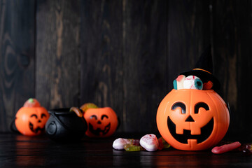 Halloween backgound with jack o lanterns pumpkins with sweets on black wooden background