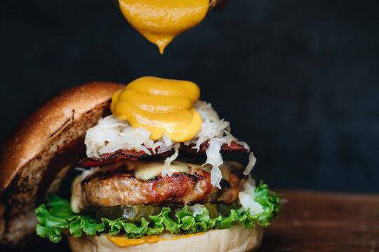 Chicken Burger With Sauerkraut, Pickles And Mustard On Wooden Board