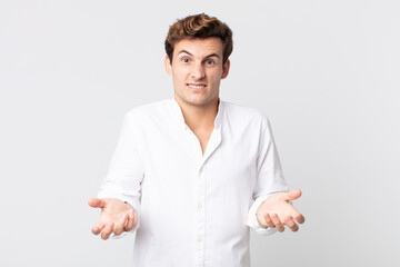 young handsome man feeling clueless and confused, not sure which choice or option to pick, wondering