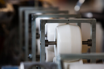 Close up photo of white plastic rolls of modern production line. Plastic pipes production machine. Absctract view.