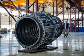 Service of steam turbines in Kazturboremont (KTR) plant. Restored iron turbine body on concrete workshop floor. Blurred worker right. Atyrau, Kazakhstan
