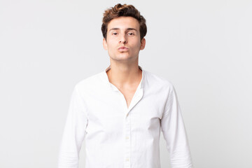 young handsome man pressing lips together with a cute, fun, happy, lovely expression, sending a kiss