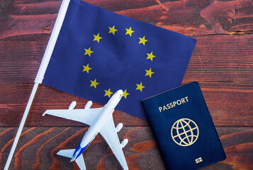 Flag of European Union  with passport and toy airplane on wooden background. Flight travel concept
