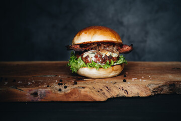 Beef burger with sauerkraut, pickles and mustard on wooden board