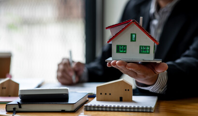 Close up house model with business man signs a purchase contract or mortgage for a home,  buy and sell home  insurance concerning mortgage loan Real estate concept.