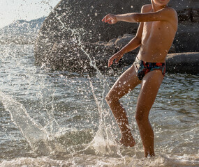 happy boy is playing splashes in the water on the beach © Anna