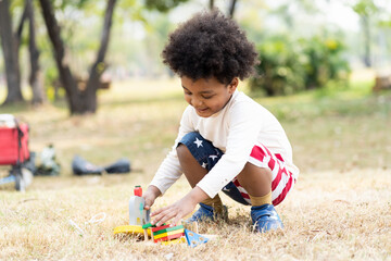 African American little boy playing toy in the park. Children with curly hair having fun outdoor....