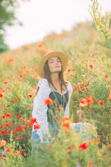 Obraz na płótnie Canvas Woman enjoys by flowering poppies on meadow.