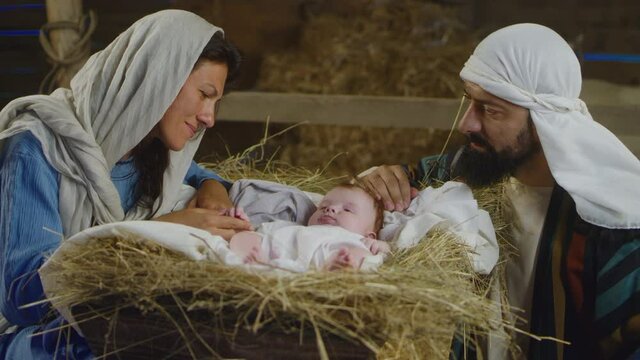 Mary and Joseph speaking with baby Jesus in manger