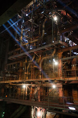 Aksu, Kazakhstan - May 29, 2012: Interior of electric power plant with light fog. Steam boiler rusted pipes. Sun rays in steamed air.