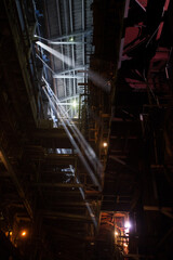 Interior of electric power plant with boiler. Welder worker down right. Sun rays in steamed air. Profile roof. Aksu, Kazakhstan.