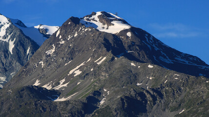 Plakat Snow capped rocky peak. View of a mountain range in summer or summer with snow at the top.