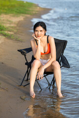 A smart woman model in red swimwear and white short pants and white shirt, she walk on the sand...