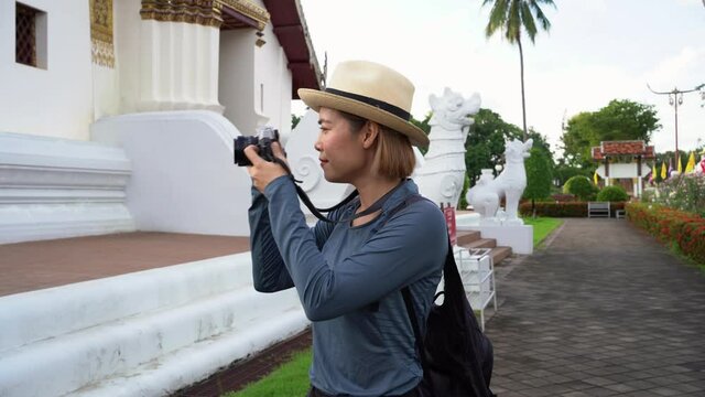 A beautiful female tourist wearing a mask, carrying a bag, holding a camera, is walking around taking pictures. tourist attraction in Nan Province, Thailand