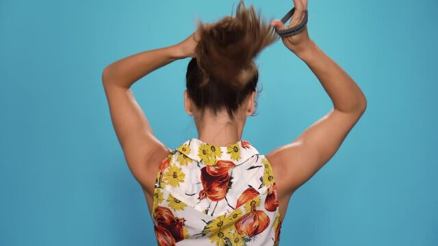 Shot of female person ties her hair.
back view