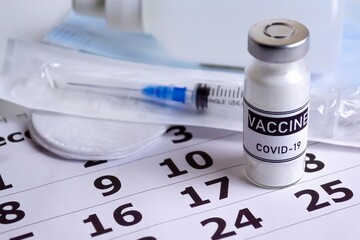 The concept of vaccination against viral diseases, prevention of covid-19. Close-up of vaccine dose on calendar background