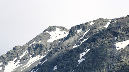 Snow capped rocky peak. View of a mountain range in summer or winter with snow at the top.