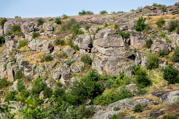 Fototapeta na wymiar mountain top with trees and granite stone ledges wildlife landscape with grass on a hillside on a summer day, a place for active tourism and hiking, nobody.