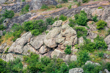 natural landscape of canyon with granite figures among grass and trees on sunny summer day, slopes with stones of highlands a place for tourism and rock climbing, nobody.