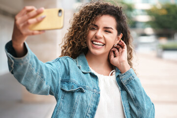 Young woman taking selfies with her mobile phone outdoors.