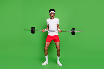 Full length body size view of trendy tired weak guy nerd sportsman lifting heavy barbell isolated over bright green color background - obrazy, fototapety, plakaty