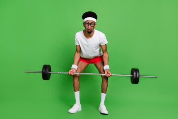 Photo of funny nerd bodybuilder guy lift heavy barbell grimace wear white t-shirt isolated green color background