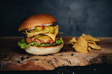 Burger with nachos and guacamole on wooden board