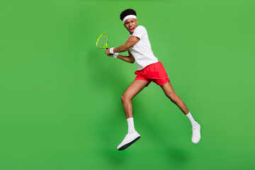 Plakat Photo of crazy tennis player guy jump hold racquet open mouth wear t-shirt shorts sneakers isolated green color background