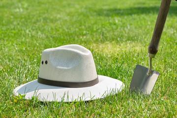 Sun hat with garden trowel or shovel in the green garden. Selective focus.
