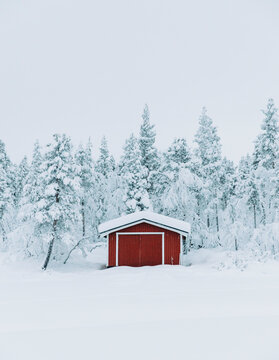 Travel lifestyle view of cute red snowy cabin in forest, near Kiruna, Lapland, Arctic Circle, Sweden.