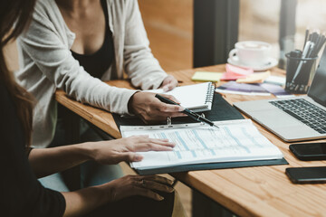 Close-up of a businesswoman hand holding a pen pointing at the document at the office.