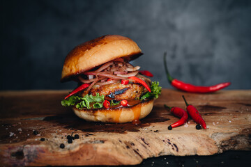 Spicy burger with marinated onions and chilli on wooden board - obrazy, fototapety, plakaty