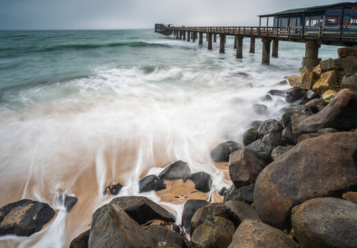 View of ocean waves crashing on the rocks near Swakopmund Jetty, a popular tourist spot, Namibia, Africa.