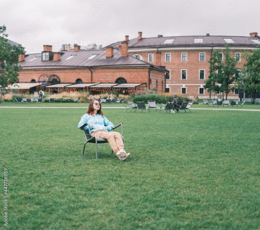 Sticker young woman relaxing in the city park little holland in summer, saint petersburg, russia.