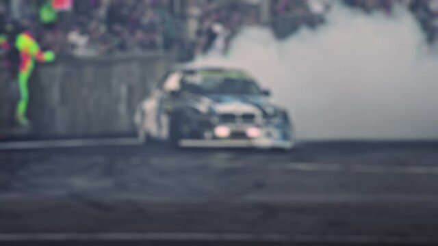 Car drifts on a sharp turn on the asphalt during the show. Racing competitions in slow motion. Smoke from under the wheels. Blurred. Professional extreme drive