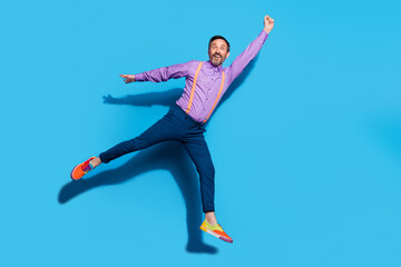 Full size profile side photo of cheerful mature man jump fly catch umbrella isolated over blue color background