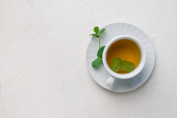 Herbal mint tea in white tea cup  and mint stalks on white background,  top view, copy space