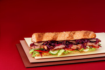 Grilled juicy baguette sandwich with fresh meat vegetables on a burgundy background. Sandwich menu. High quality photo