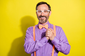 Photo of handsome mature man happy positive smile hold hands together formalwear isolated over yellow color background